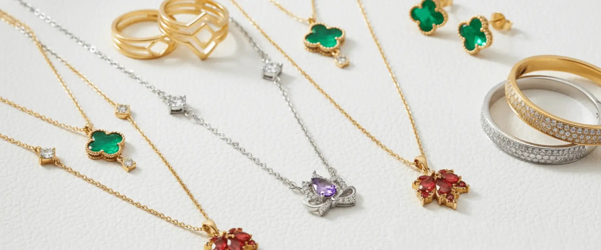 Collection of gold and silver jewelry with gemstones on a light background